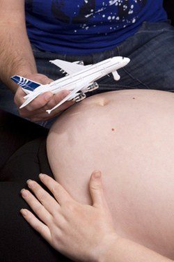 Mujer embarazada junto un avión de juguete