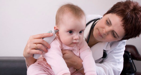 Pediatra tomando la fiebre a un bebé